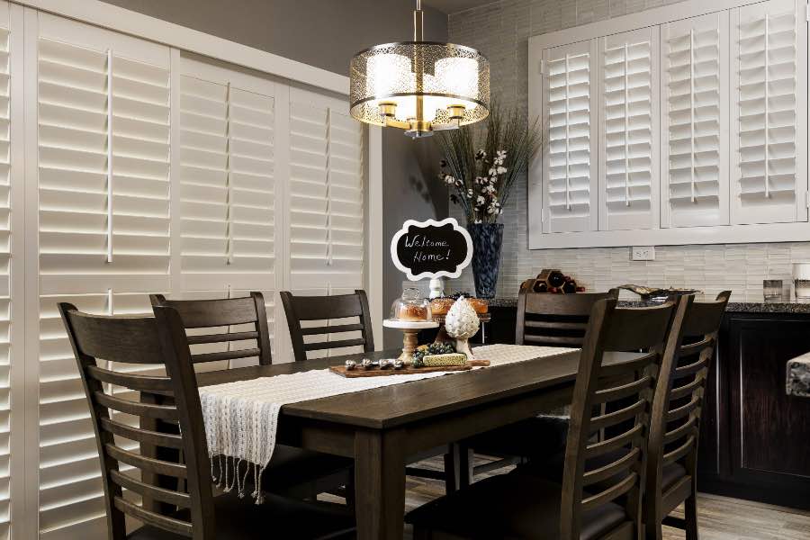 White Polywood shutters on a sliding patio door in a dining room